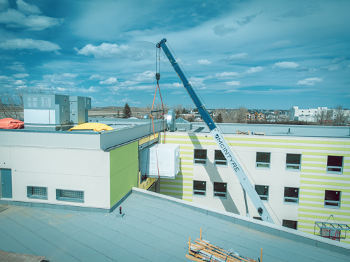 crane hoisting ahu unit into building